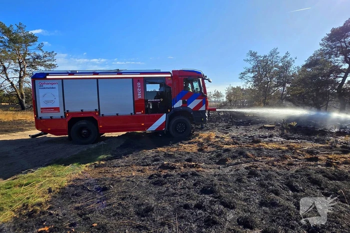 Brandweer blust smeulende resten in afgebrande heidegebied