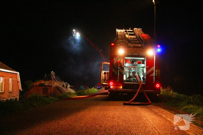 Brandweerlieden trekken rietendak uit elkaar om brand te kunnen bestrijden