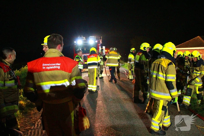 Brandweerlieden trekken rietendak uit elkaar om brand te kunnen bestrijden