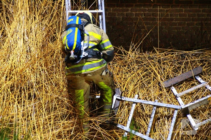 Brandweerlieden trekken rietendak uit elkaar om brand te kunnen bestrijden