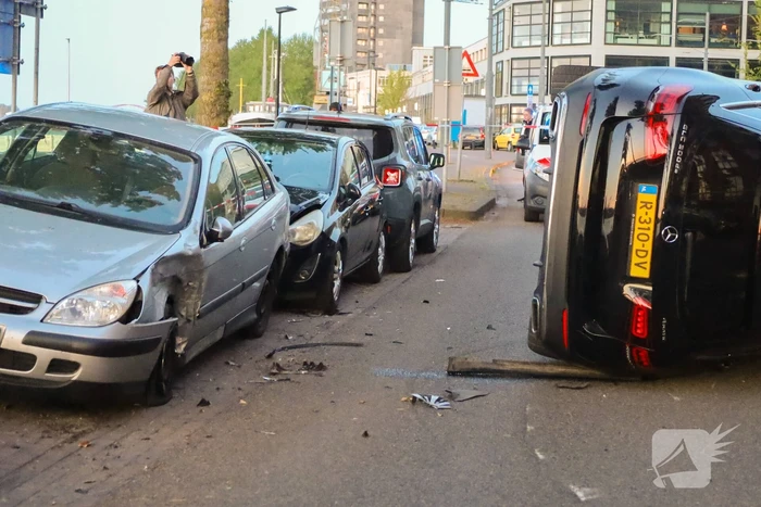 Auto botst op drie geparkeerde auto's en belandt op zijkant