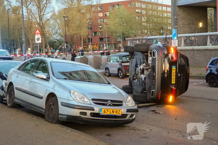 Auto botst op drie geparkeerde auto's en belandt op zijkant