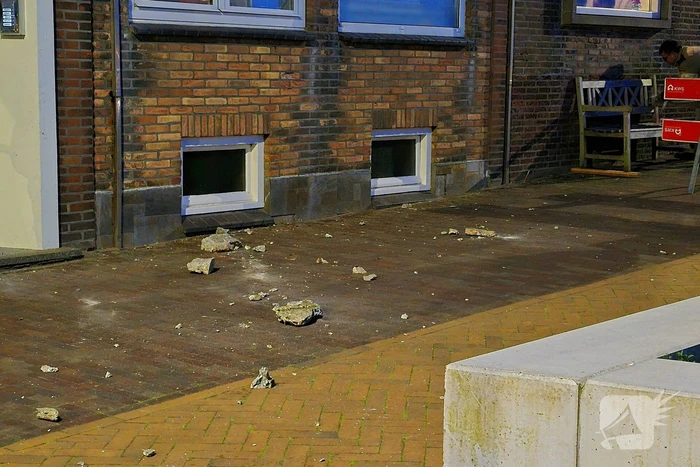 Brokstukken op stoep van gevel