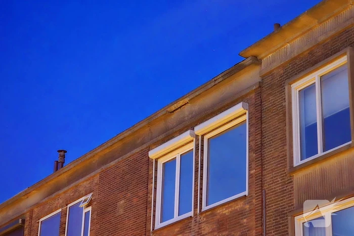 Brokstukken op stoep van gevel