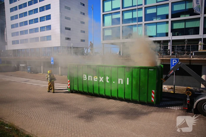 Vlammen slaan uit grote afvalcontainer