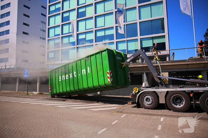 Vlammen slaan uit grote afvalcontainer