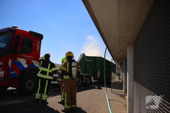 Vlammen slaan uit grote afvalcontainer