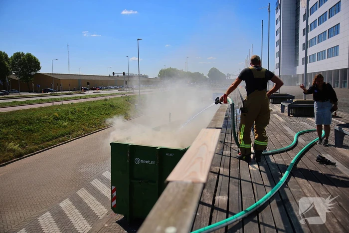 Vlammen slaan uit grote afvalcontainer