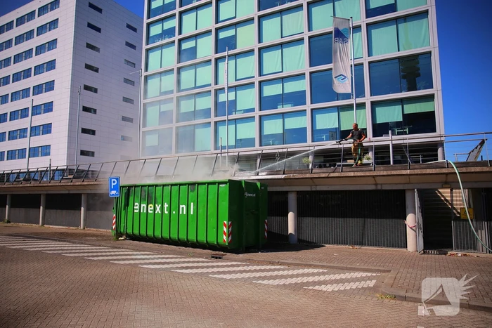 Vlammen slaan uit grote afvalcontainer