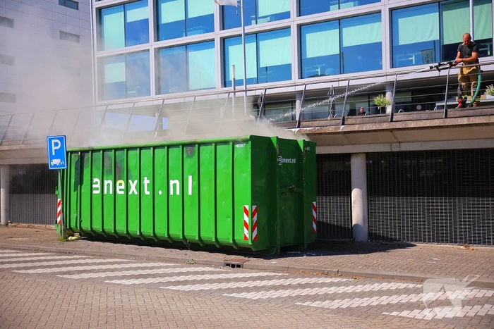 Vlammen slaan uit grote afvalcontainer