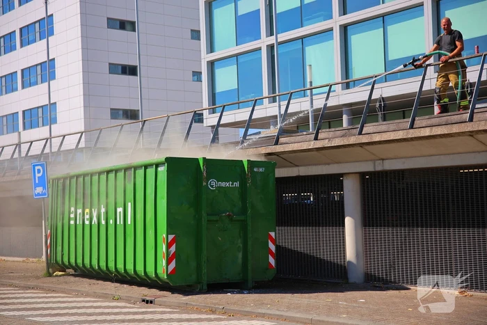 Vlammen slaan uit grote afvalcontainer