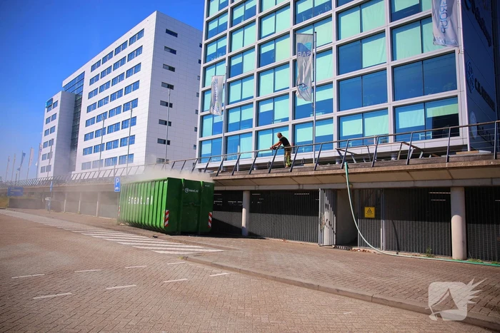 Vlammen slaan uit grote afvalcontainer
