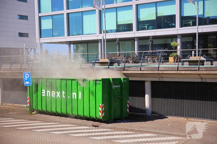 Vlammen slaan uit grote afvalcontainer