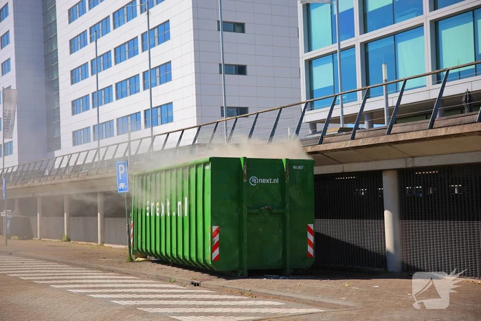 Vlammen slaan uit grote afvalcontainer