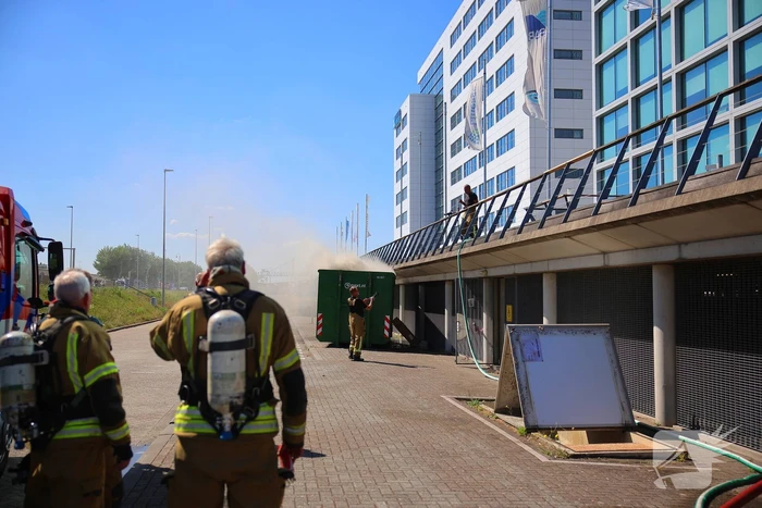 Vlammen slaan uit grote afvalcontainer