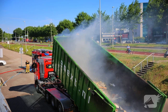 Vlammen slaan uit grote afvalcontainer