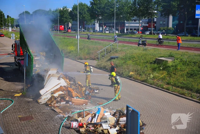 Vlammen slaan uit grote afvalcontainer