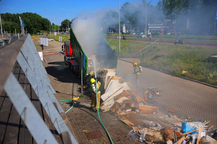 Vlammen slaan uit grote afvalcontainer