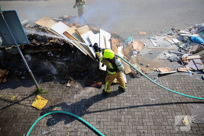 Vlammen slaan uit grote afvalcontainer