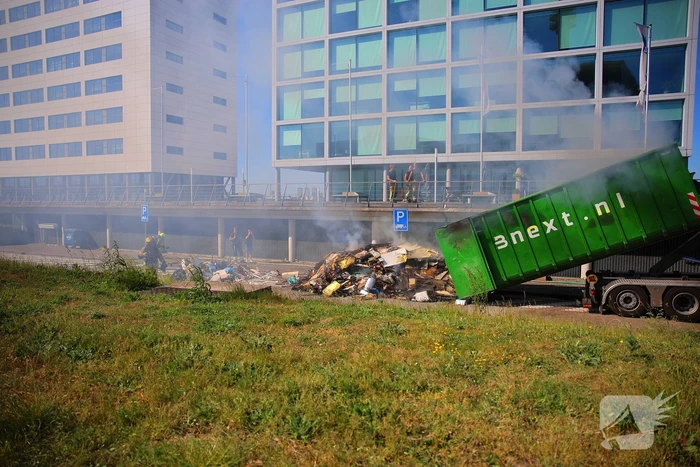 Vlammen slaan uit grote afvalcontainer