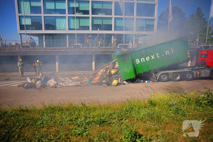 Vlammen slaan uit grote afvalcontainer