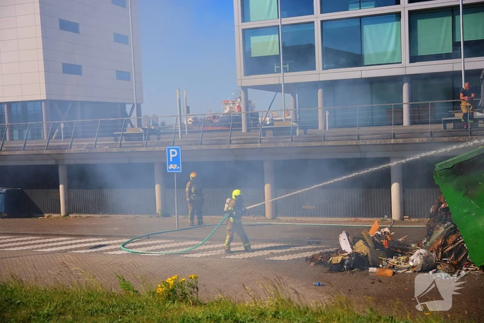 Vlammen slaan uit grote afvalcontainer