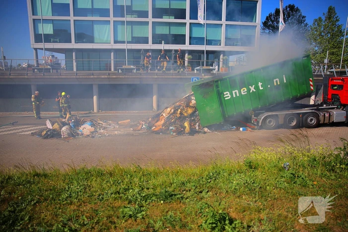 Vlammen slaan uit grote afvalcontainer