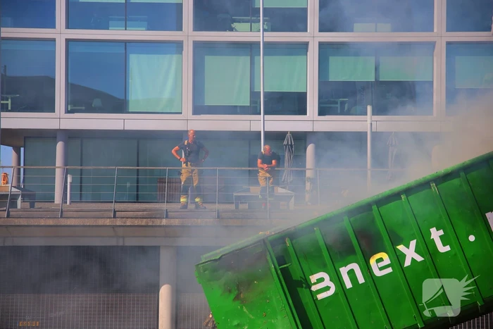 Vlammen slaan uit grote afvalcontainer