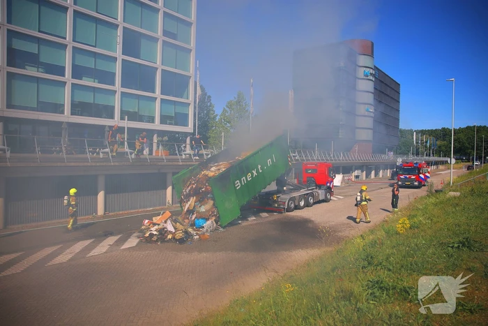 Vlammen slaan uit grote afvalcontainer