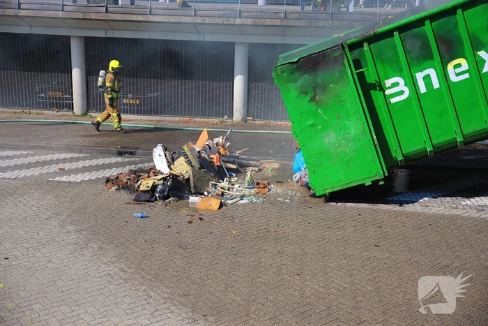 Vlammen slaan uit grote afvalcontainer