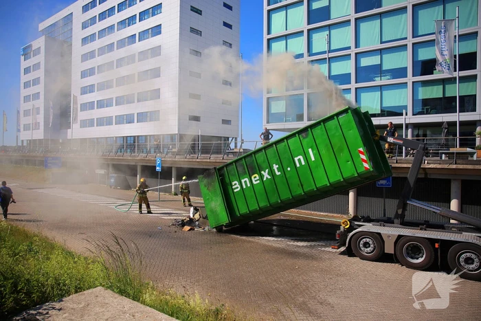 Vlammen slaan uit grote afvalcontainer
