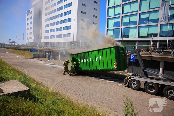Vlammen slaan uit grote afvalcontainer