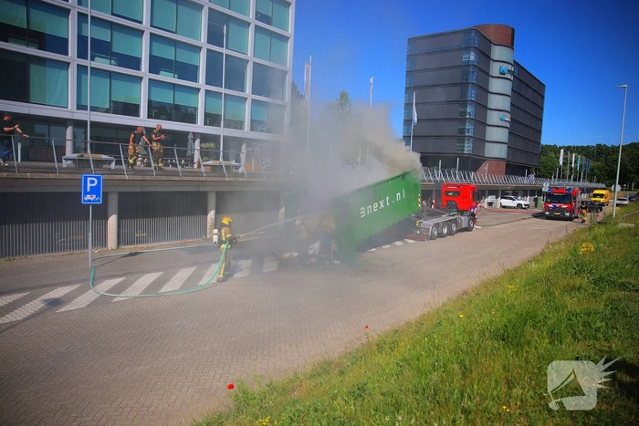 Vlammen slaan uit grote afvalcontainer