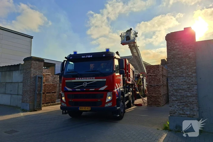 Palletopslag in brand, gebouw bedreigt