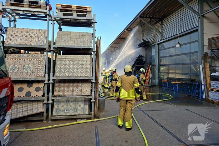 Palletopslag in brand, gebouw bedreigt