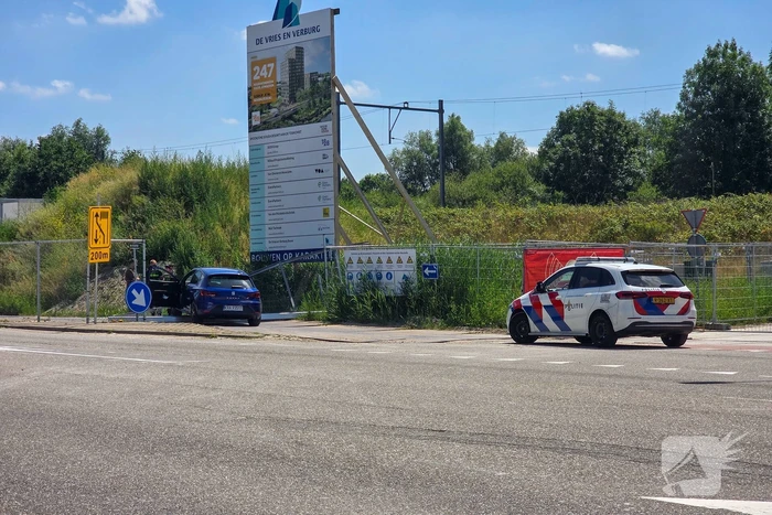 Automobilist ramt hekwerk bij bouwplaats