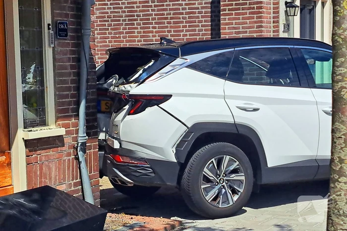 Auto rijdt achteruit tegen woning