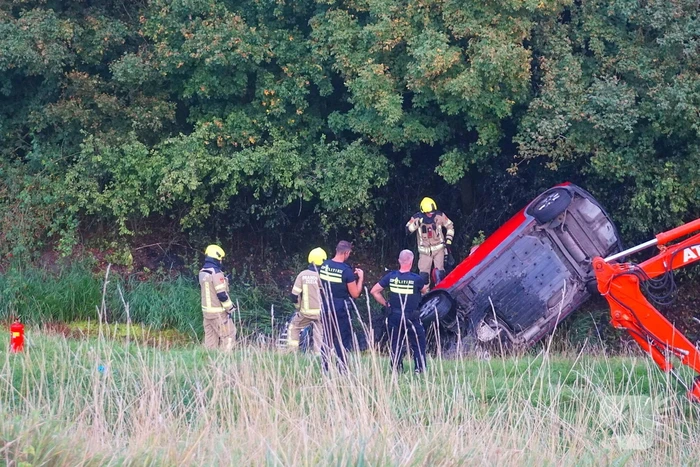 Auto rijdt van dijk af en slaat voorover