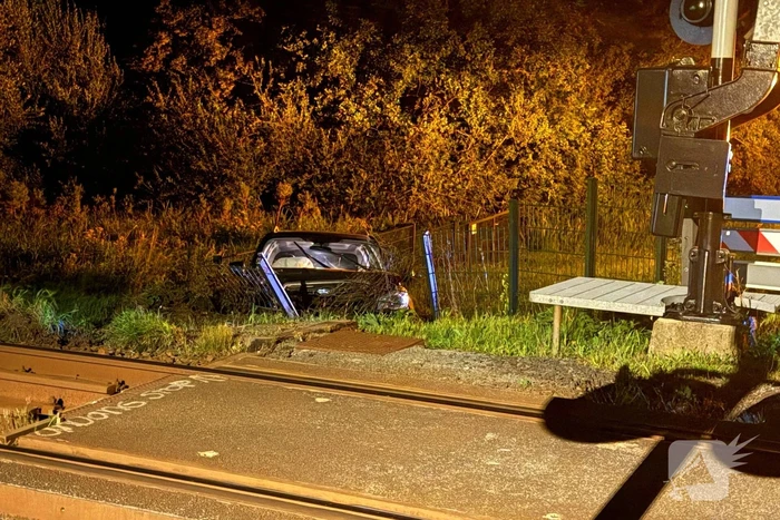 Auto vliegt uit de bocht en knalt tegen hek bij spoorwegovergang