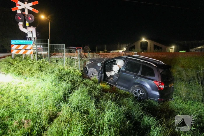 Auto vliegt uit de bocht en knalt tegen hek bij spoorwegovergang