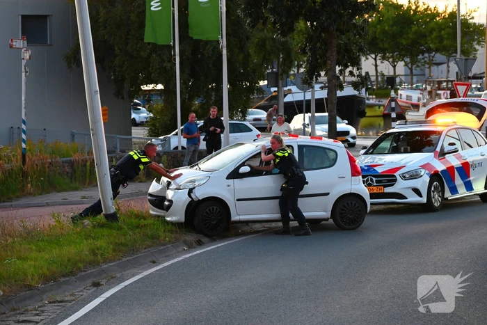 Auto crasht op rotonde en raakt paal