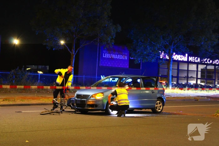 Fiets belandt onder auto bumper
