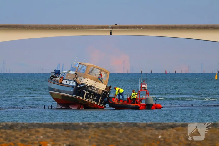 Boot loopt vast op dam, bergingsbedrijf schiet te hulp