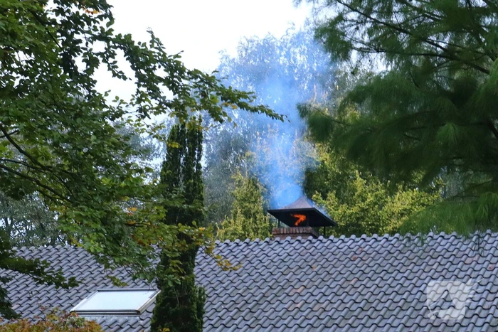 Vlammen slaan uit schoorsteen