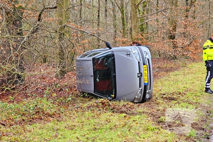 Auto belandt op zijkant naast weg