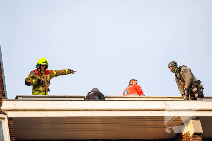 Man gooit voorwerpen van dak, politie team haalt man van dak
