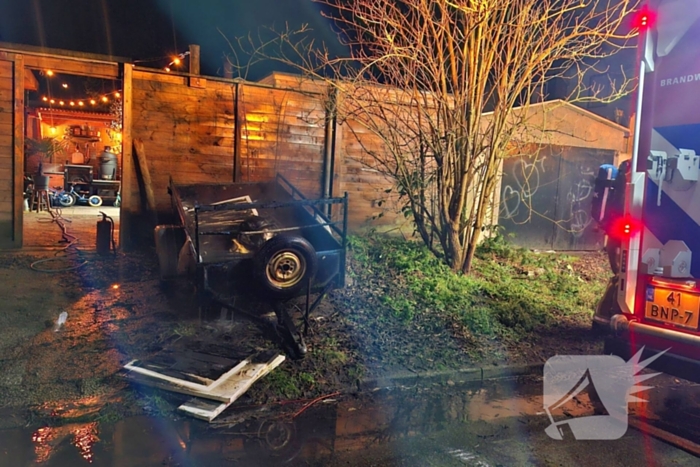 Vlammen slaan uit aanhanger, buurtbewoner start blussing