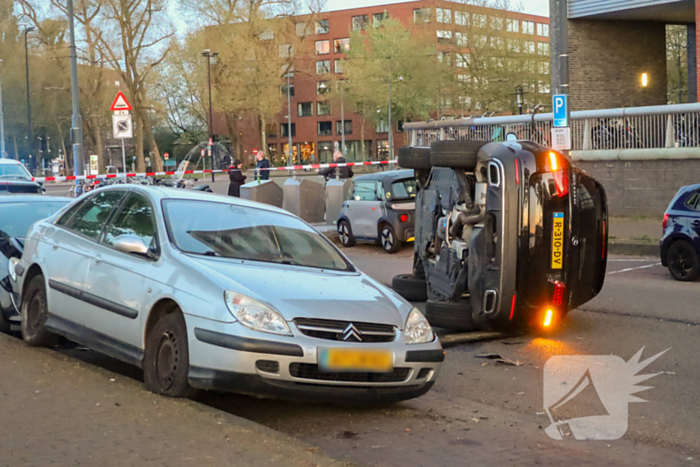Auto botst op drie geparkeerde auto's en belandt op zijkant