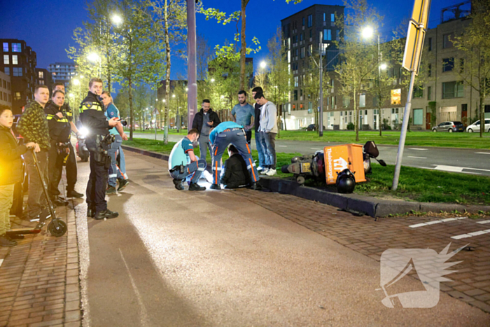 Maaltijdbezorger klapt tegen auto en komt ten val