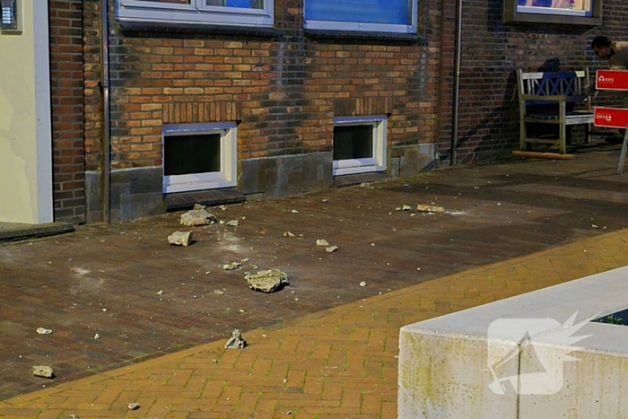 Brokstukken op stoep van gevel